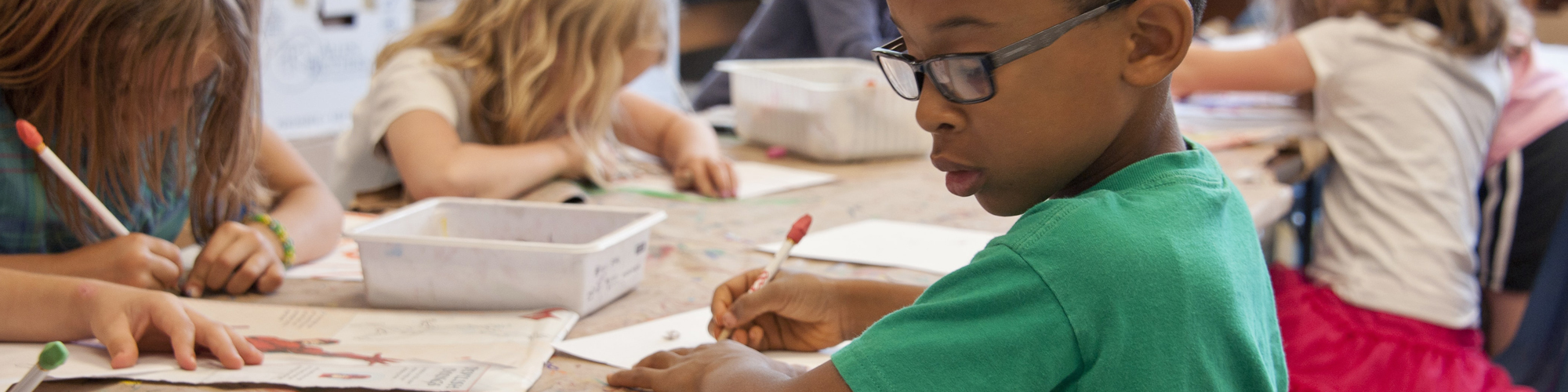 Flera barn som sitter vid ett bord och ritar och skriver