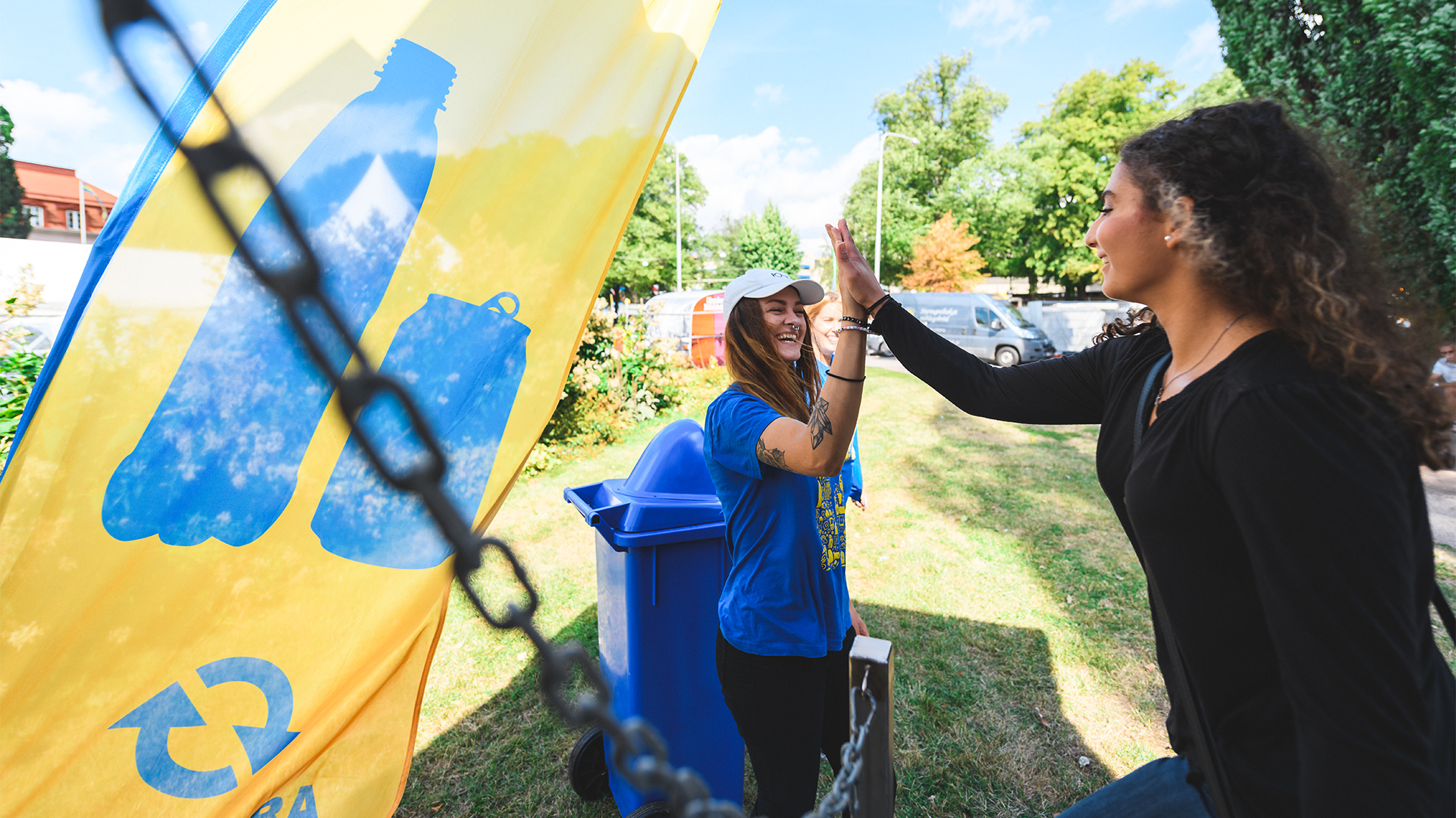 Två unga kvinnor gör high-five vid en Pantamera beachflagga