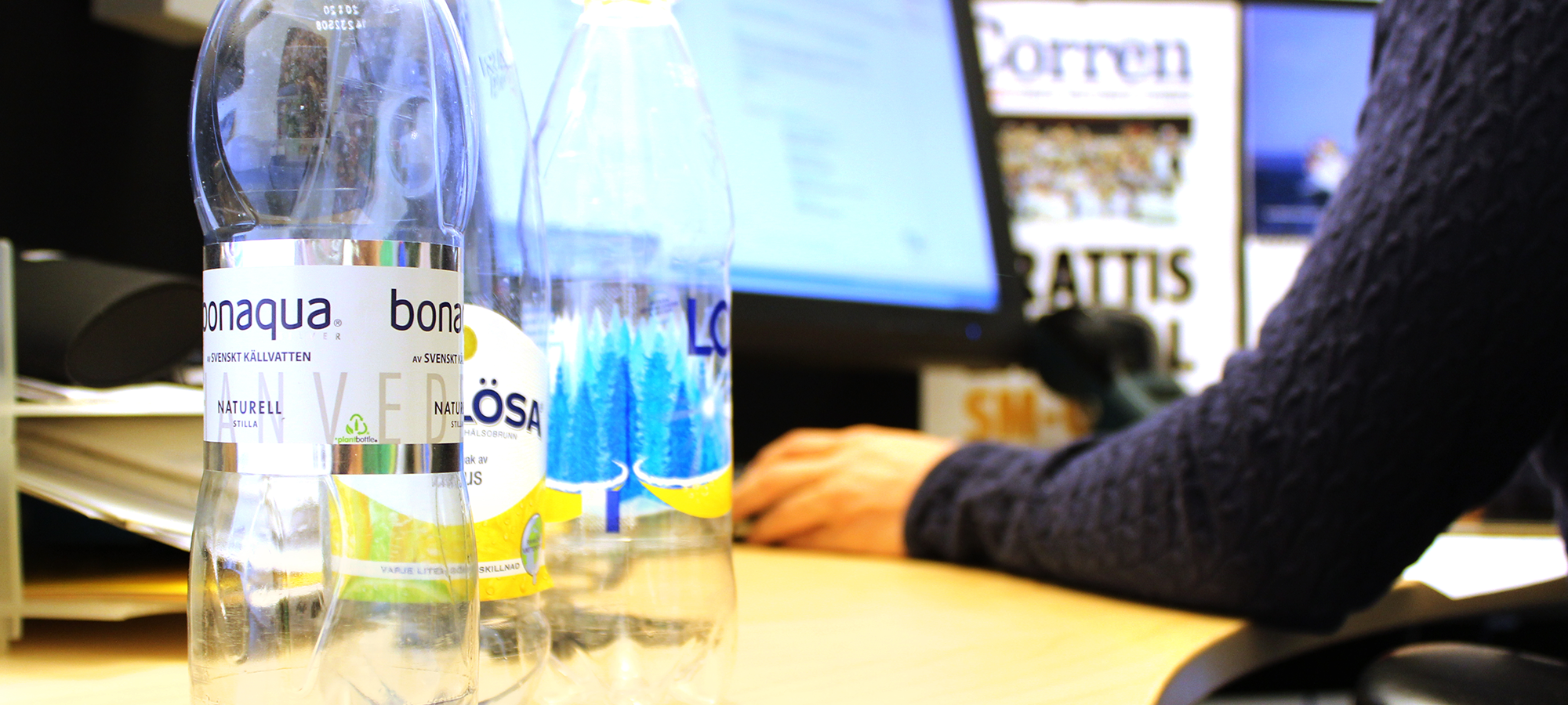 Person framför dator med pantflaskor bredvid sig